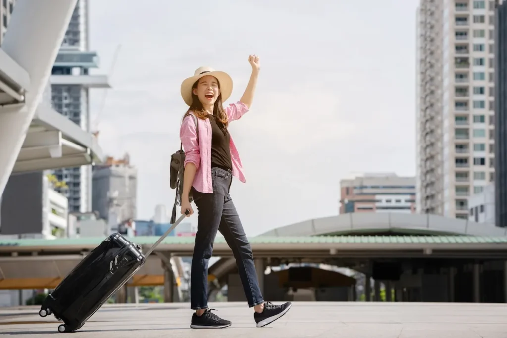 Asian women tourist wear casual clothes wear hat and black luggage. Travel during long summer holidays using city public transport as train, airplane or bus. Which has comfortable feeling in traveling